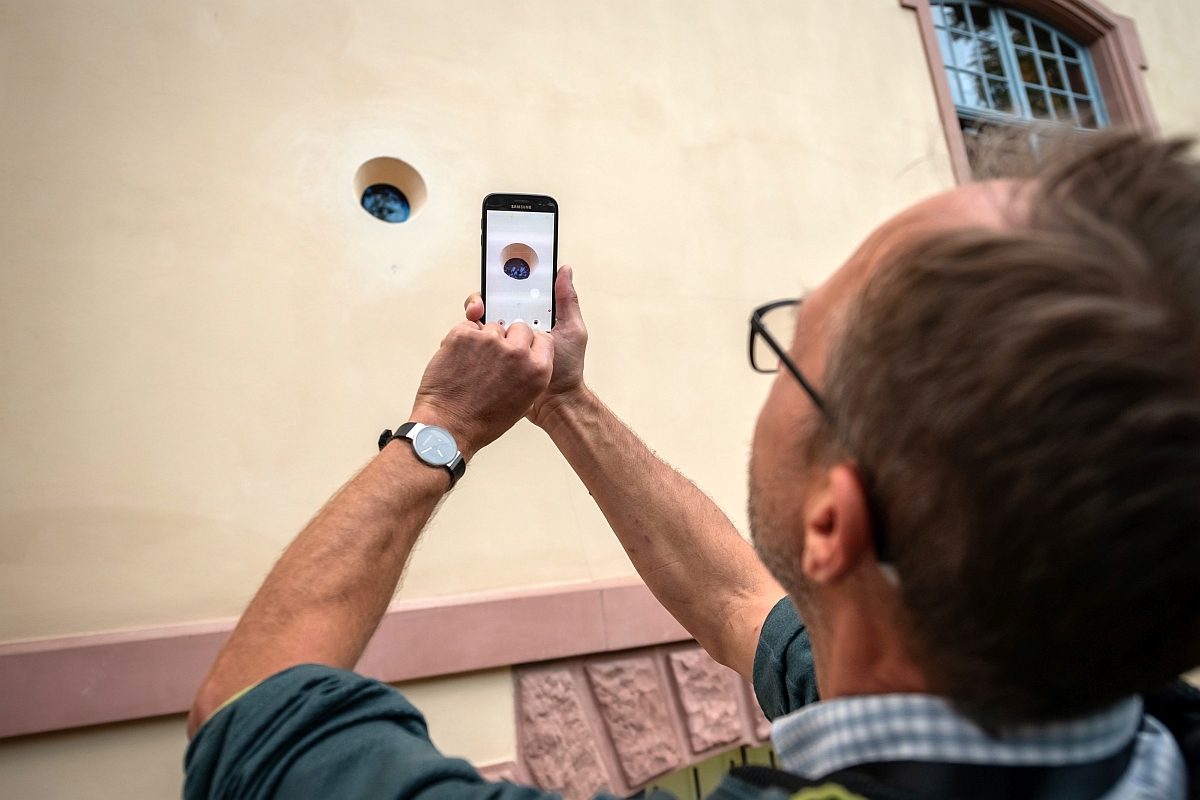 Besucher fotografiert das Bohrloch in der Villa Rosenthal mit seinem Smartphone
