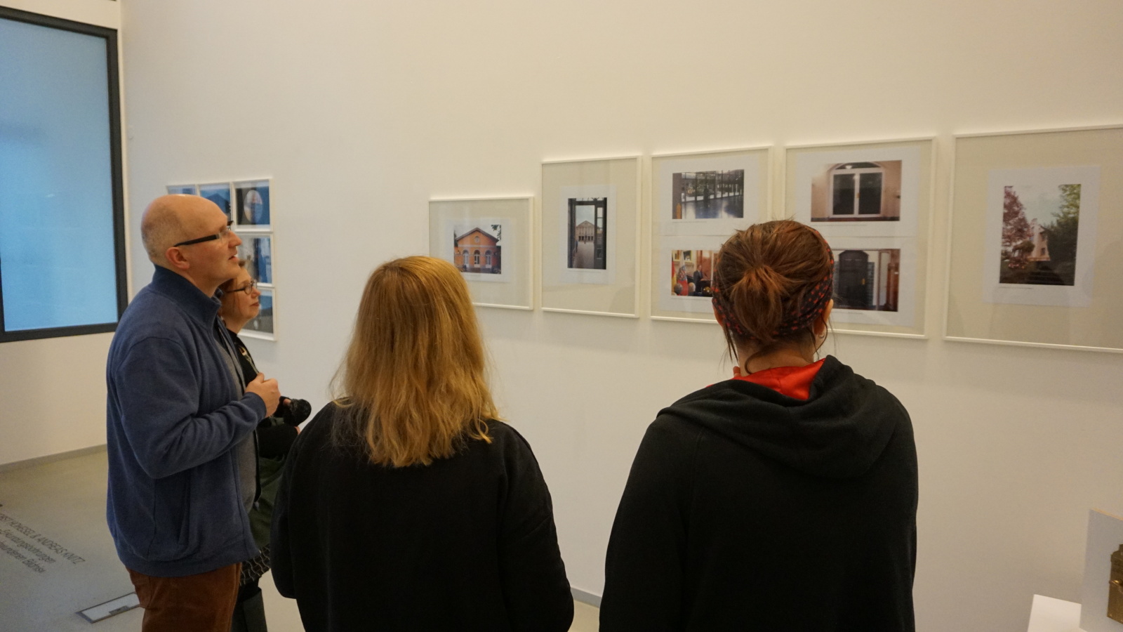 Vier Menschen in Rückansicht beim Betrachten von Bildern in der Ausstellung zum Kunstpreis 2018.