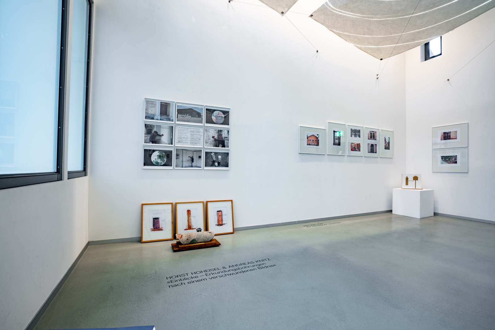 Der obere Ausstellungsraum des Jenaer Kunstverein: In dem hellen Raum ist Links der Entwürf von Hoheisel und Knitz mit dem Bohrkern im Zentrum und im Hintergrund, rechts davon der Entwurf von Antonia Low mit der Türklinke zu sehen.